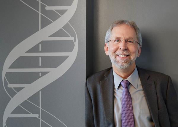 Dr. Eric Green next to a drawing of a DNA molecule